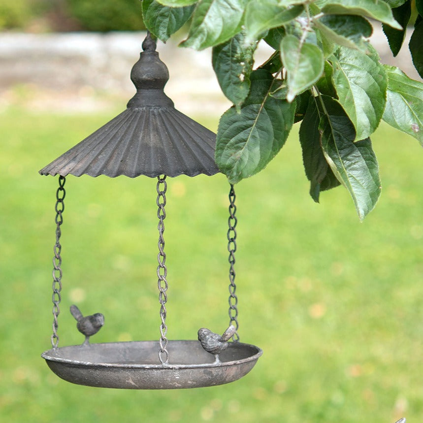 Abreuvoir oiseaux en métal gris avec toit suspendu dans jardin bucolique ambiance naturelle