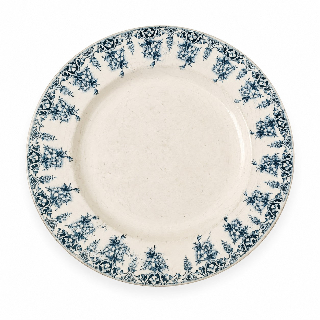 Assiette creuse ancienne en terre de fer modèle Primevère, décor floral bleu, commercialisée pour les Nouvelles Galeries à la fin du XIXᵉ siècle.