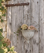 Cache-pot mural en métal gris patiné pour fleurs et plantes, décoration romantique et maison de caractère.