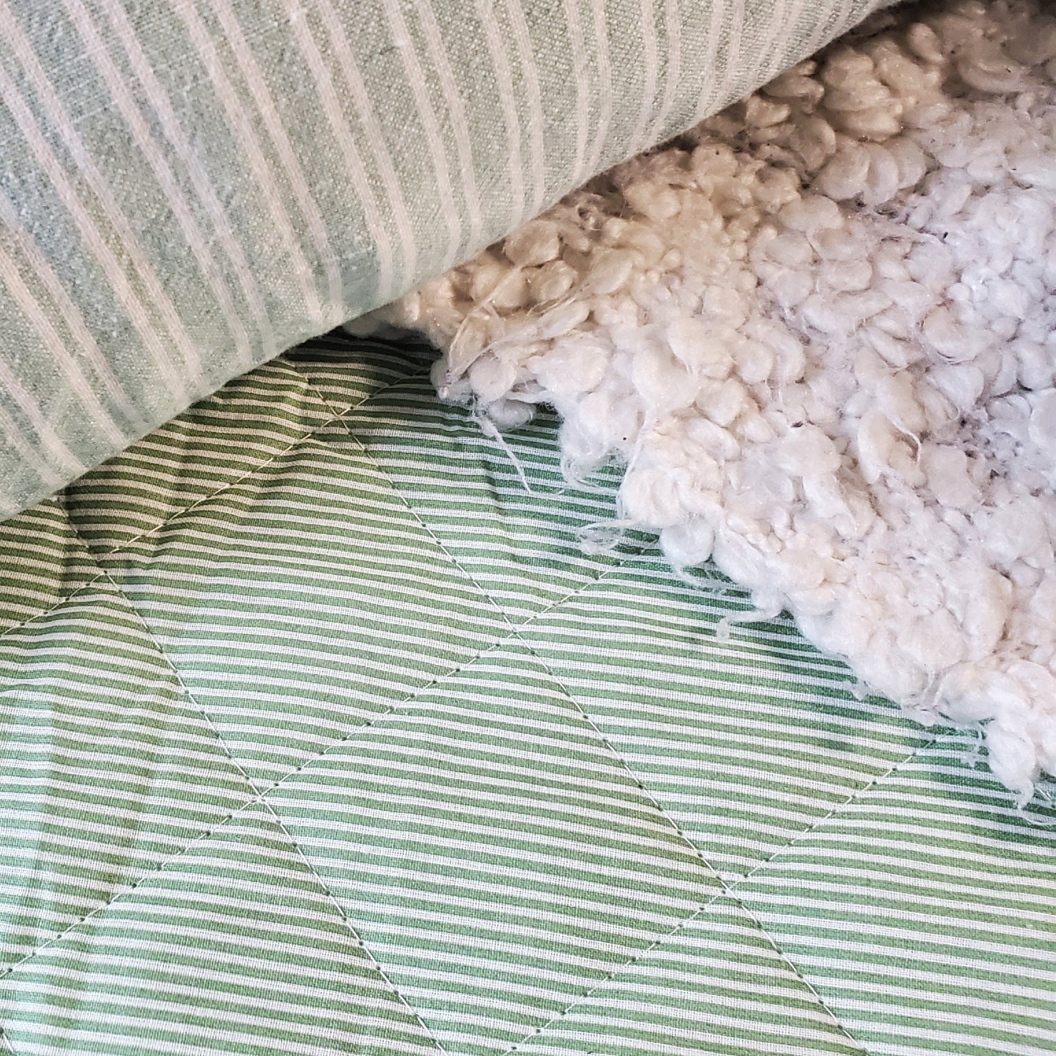 Détail d’une couverture piquée en coton rayures vert et blanc, style farmhouse élégant et décoration naturelle
