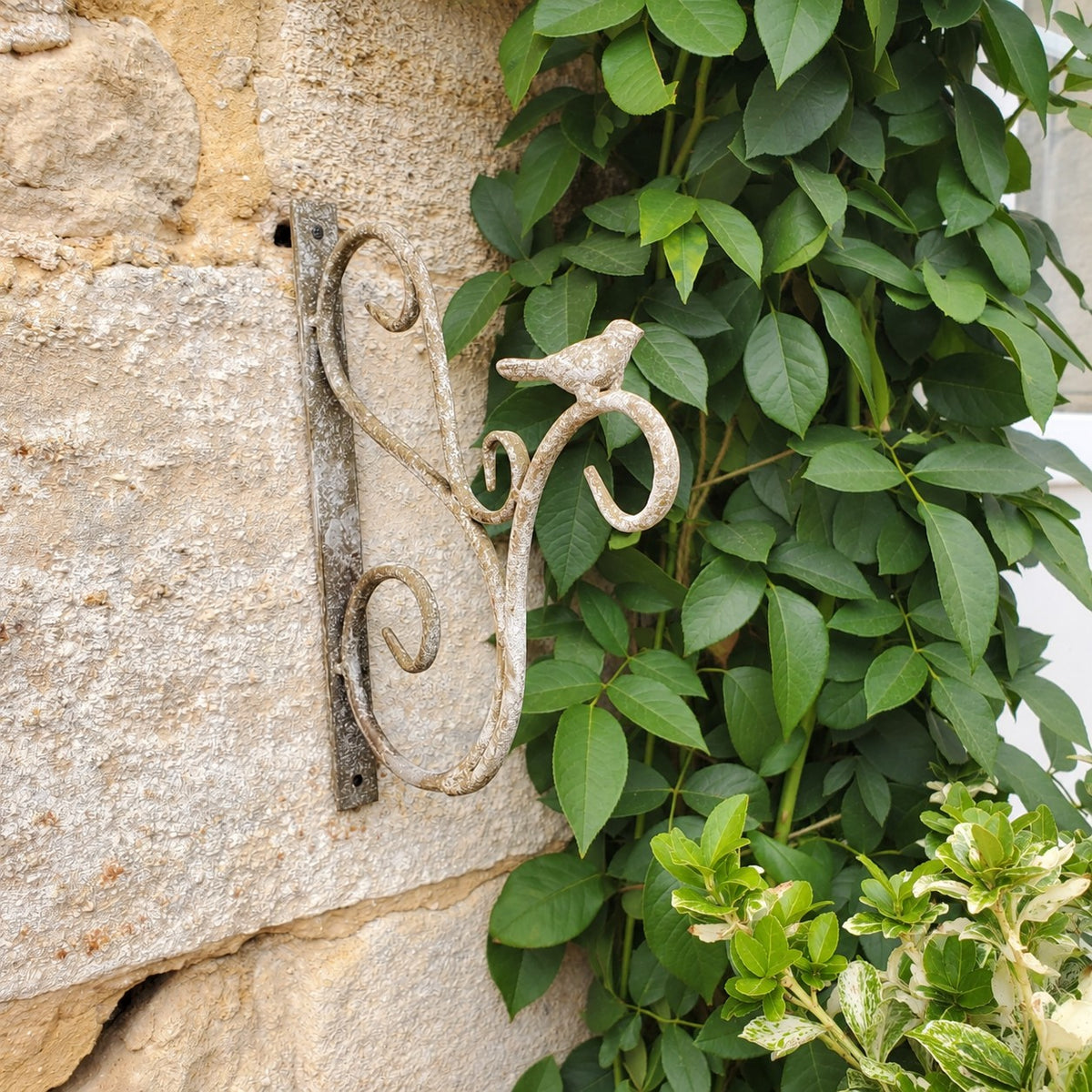 Crochet de jardin en métal patiné gris pour décorer un mur extérieur dans un esprit maison de charme.