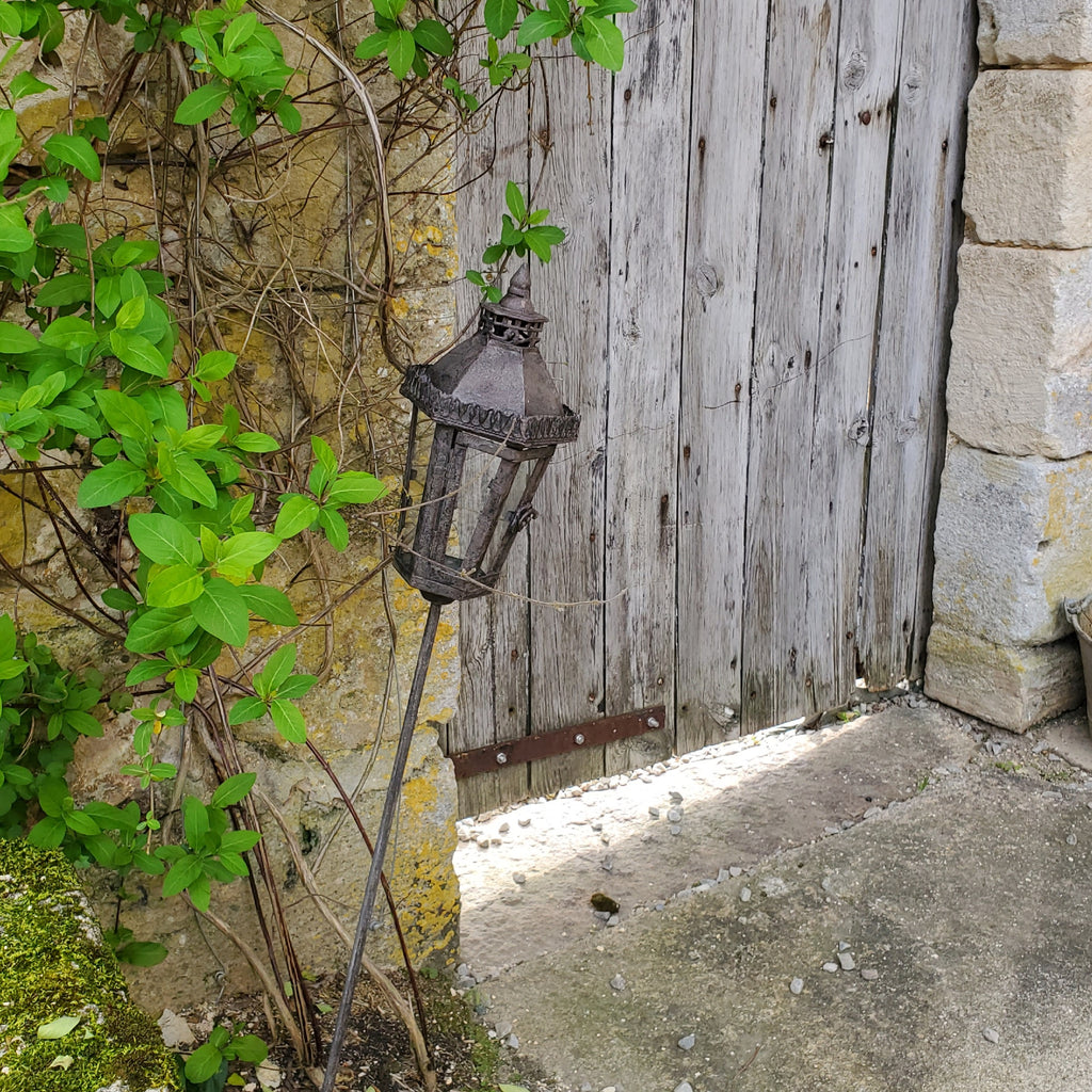 Lanterne en métal et verre plantée dans un jardin, ambiance chaleureuse campagne chic