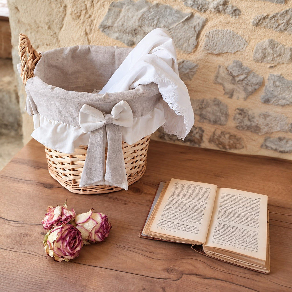 Panier en osier décoré d’un grand nœud et d’un volant en tissu écru.