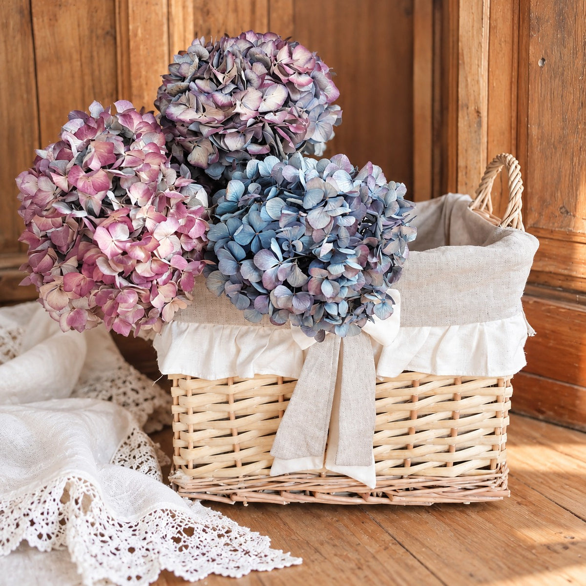 Grand panier en osier décoré d’un nœud et d’un volant en tissu écru.
