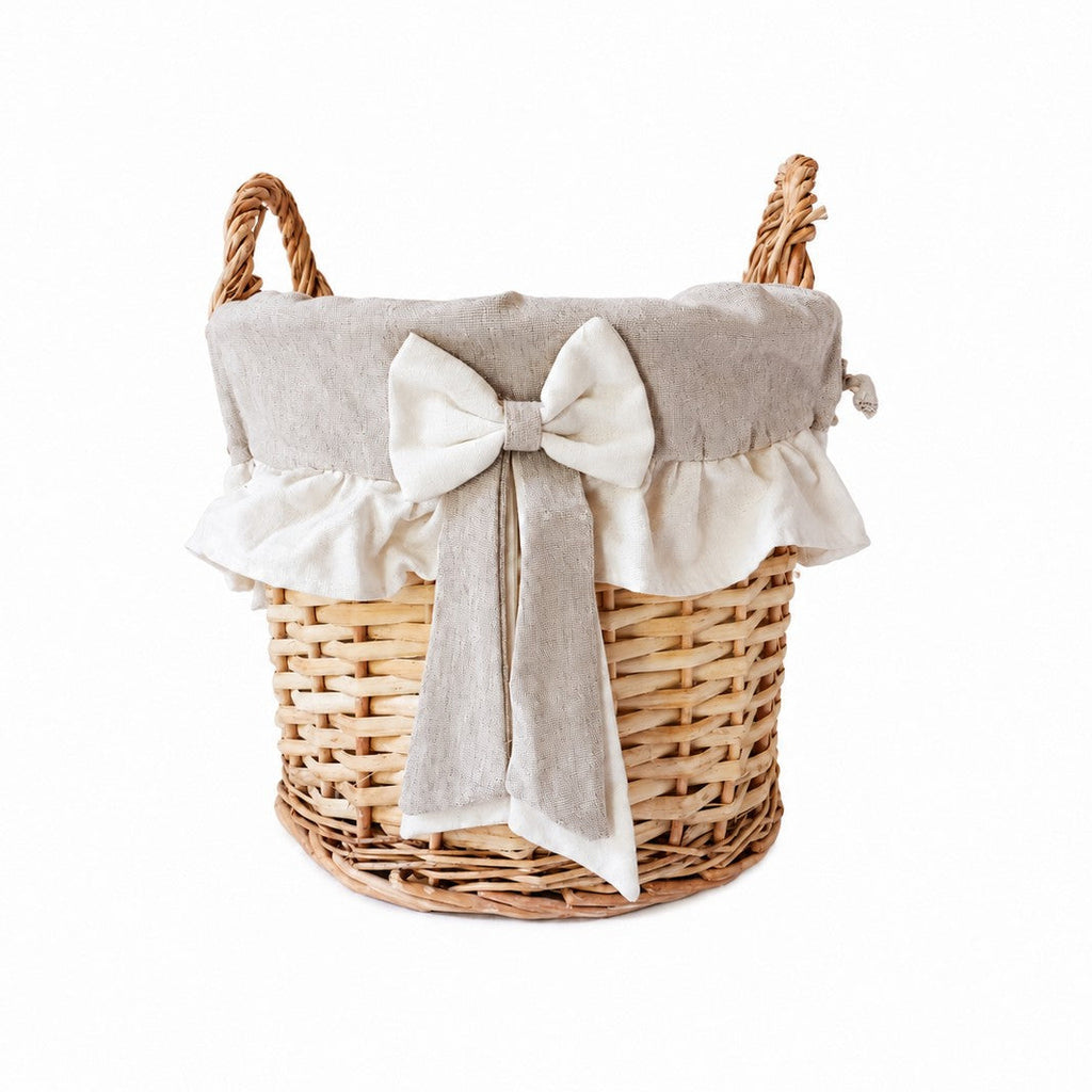 Panier rond en osier avec doublure en tissu naturel, volant et nœud décoratif.